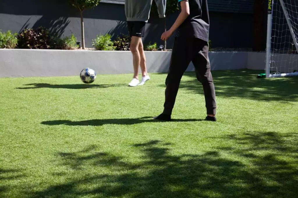 Kids playing soccer in a ground made of artificial turf